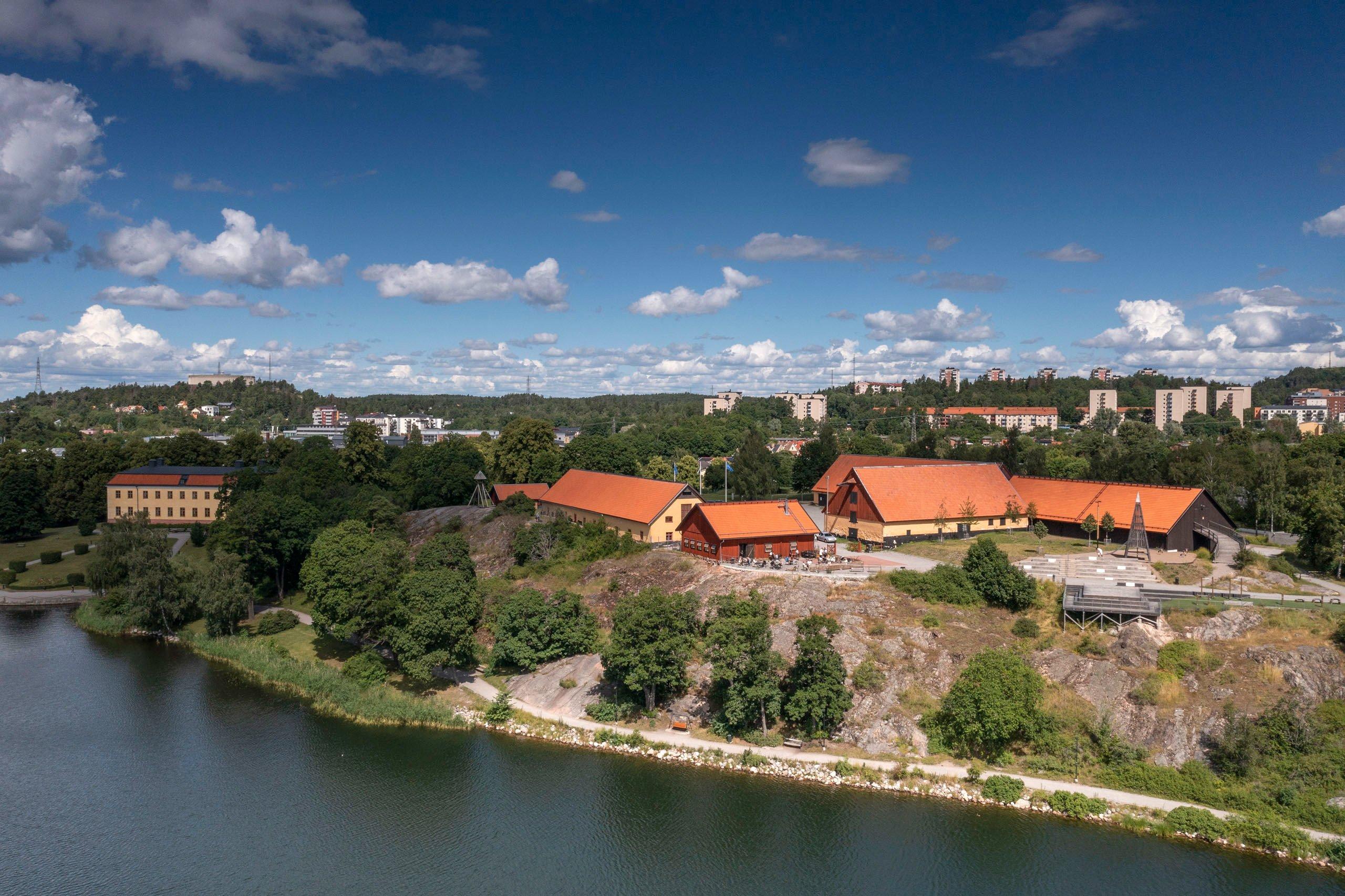 Slott och stallbyggnader med utsikt över vattnet.