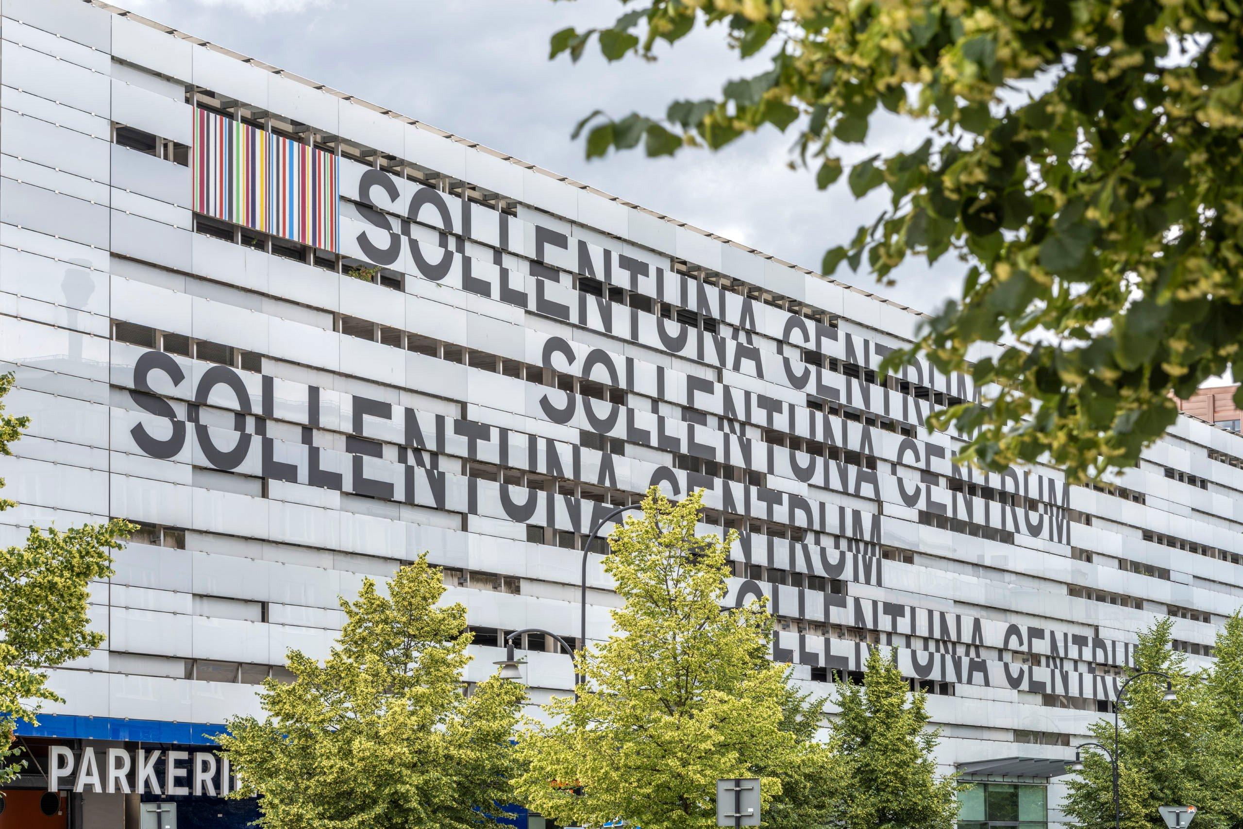 Fasad på stor vit byggnad med texten "Sollentuna Centrum" på.